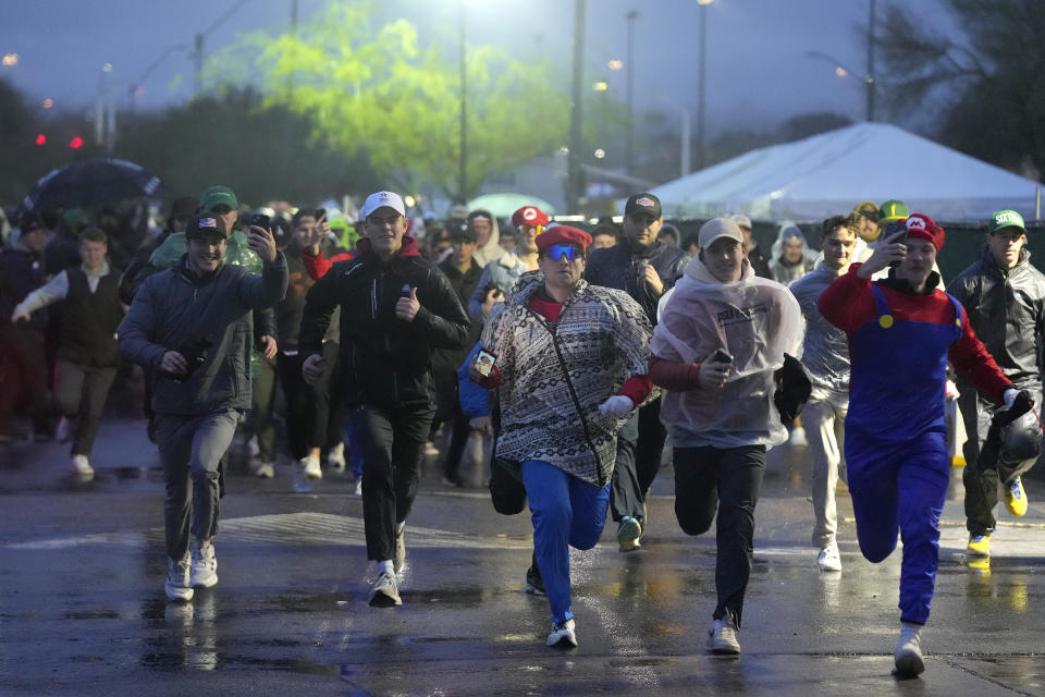 Fans run onto the course prior to the continuation of second round of the Phoenix Open golf tournament Saturday, Feb. 10, 2024, in Scottsdale, Ariz. (AP Photo/Ross D. Franklin)