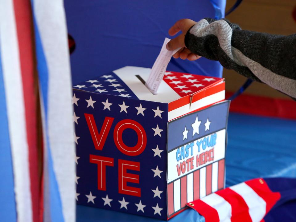 A student places a ballot into the voting box during a mock election at a school in Gainesville in 2020.