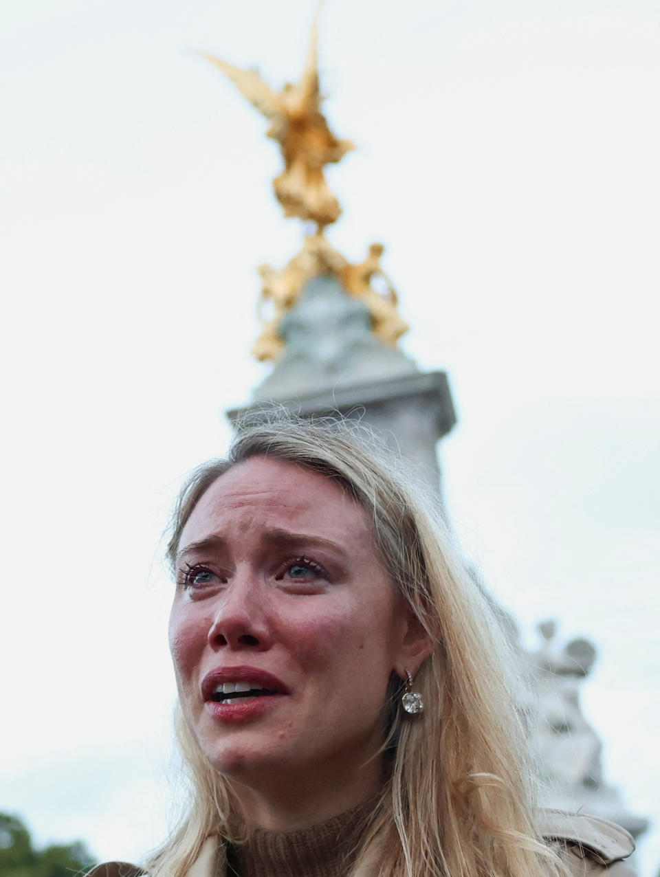 A woman reacts in front of Queen Victoria memorial outside the Buckingham Palace, after Queen Elizabeth, Britain's longest-reigning monarch and the nation's figurehead for seven decades, died aged 96, in London, Britain September 8, 2022. REUTERS/Henry Nicholls