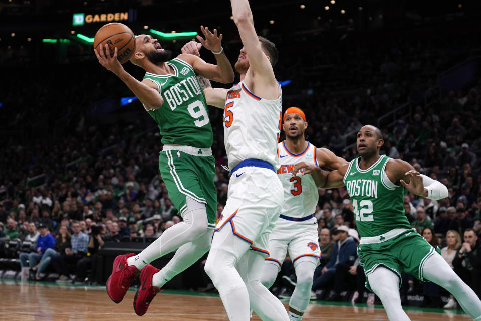 Boston Celtics guard Derrick White (9) drives to the basket against New York Knicks center Isaiah Hartenstein, center, during the first half of an NBA basketball game, Friday, Dec. 8, 2023, in Boston. (AP Photo/Charles Krupa)