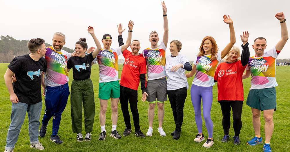 A group of runners stand side-by-side and cheer for the Dublin 5K Pride Run.