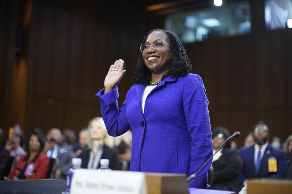 Jackson, raising her right hand and smiling, is sworn in to her confirmation hearing. 