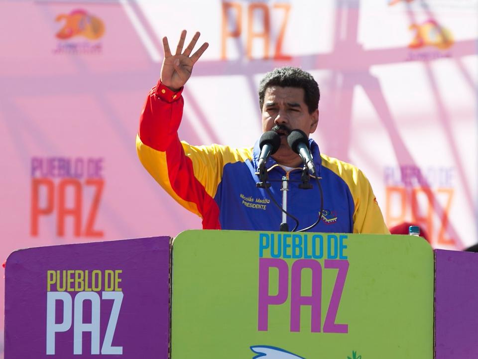 Venezuela's President Nicolas Maduro speaks during a rally on Bolivar Avenue in downtown Caracas, Venezuela, Saturday, Feb. 15, 2014. The signs read in Spanish "People of peace." Maduro said a police manhunt is underway for opposition leader Leopoldo Lopez, and denounced what he said is a "fascist" plot to oust him from power. (AP Photo/Alejandro Cegarra)