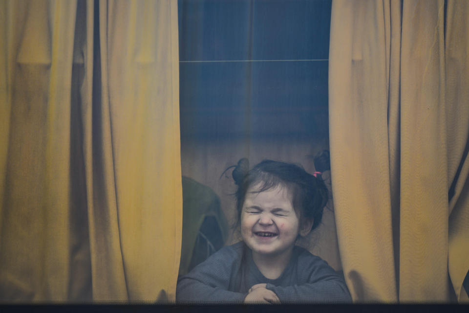 FILE - A child refugee fleeing the war from neighboring Ukraine with her family smiles as she presses her nose against a bus window after crossing the border by ferry at the Isaccea-Orlivka border crossing, in Romania, Friday, March 25, 2022. Since Russia launched its attacks against Ukraine on Feb. 24, more than 6 million people have fled war-torn Ukraine, the United Nations refugee agency announced Thursday, May 12, 2022. (AP Photo/Andreea Alexandru, File)