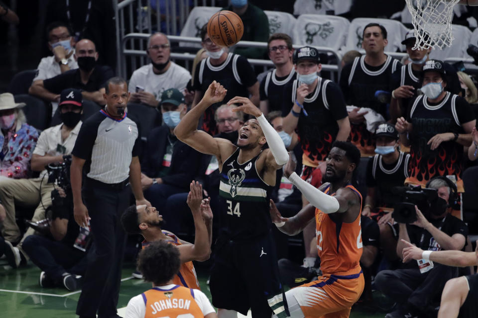 Milwaukee Bucks forward Giannis Antetokounmpo (34) battles between Phoenix Suns forward Cameron Johnson and Phoenix Suns center Deandre Ayton (22) during the first half of Game 6 of basketball's NBA Finals Tuesday, July 20, 2021, in Milwaukee. (AP Photo/Aaron Gash)