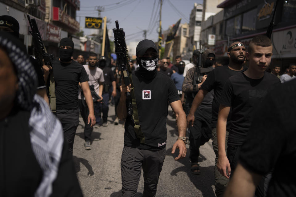 Gunmen march as mourners carry the bodies of Palestinians, some draped in the Islamic Jihad militant group flags during their funeral in the West Bank city of Jenin, Thursday, May 23, 2024. The Israeli military said Thursday it has completed a two-day operation in the occupied West Bank that the Palestinian Health Ministry says killed 12 Palestinians. Militant groups claimed at least eight of the dead as fighters, one from Hamas and seven from the Al-Aqsa Martyrs Brigade. (AP Photo/Leo Correa)