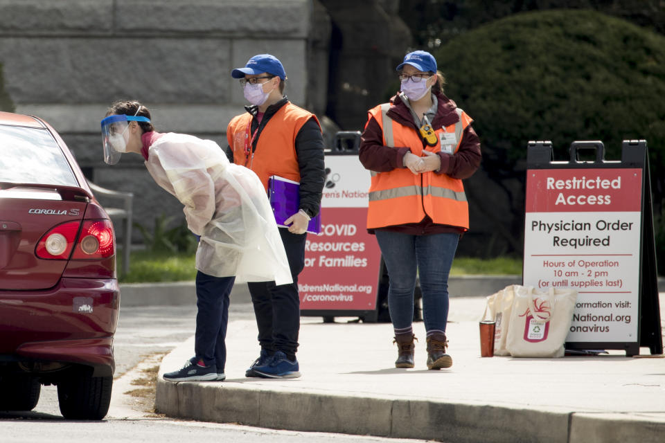 Workers direct people as Children's National Hospital tests children and young adults for COVID-19 at a drive-through (drive-in) testing site at Trinity University, Thursday, April 16, 2020, in Washington. (AP Photo/Andrew Harnik)