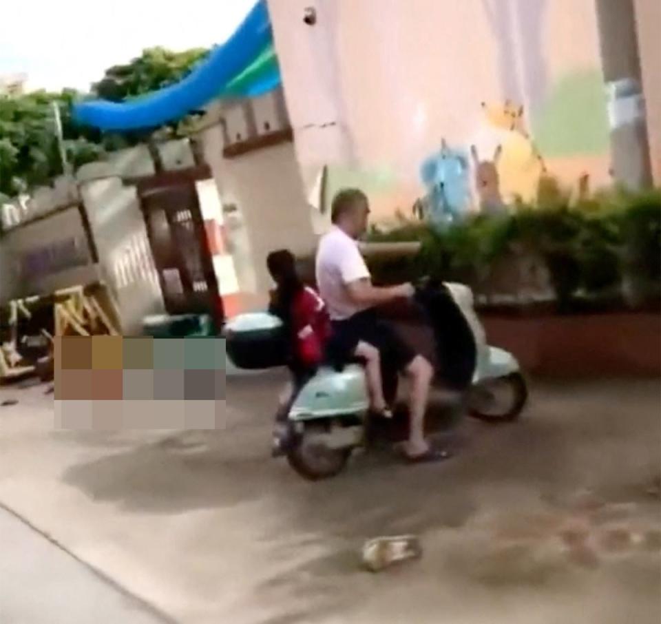 A body lies on the ground near people riding a scooter in the aftermath of a stabbing attack at a kindergarten in Lianjiang county, Guangdong province, China (Video obtained via REUTERS)