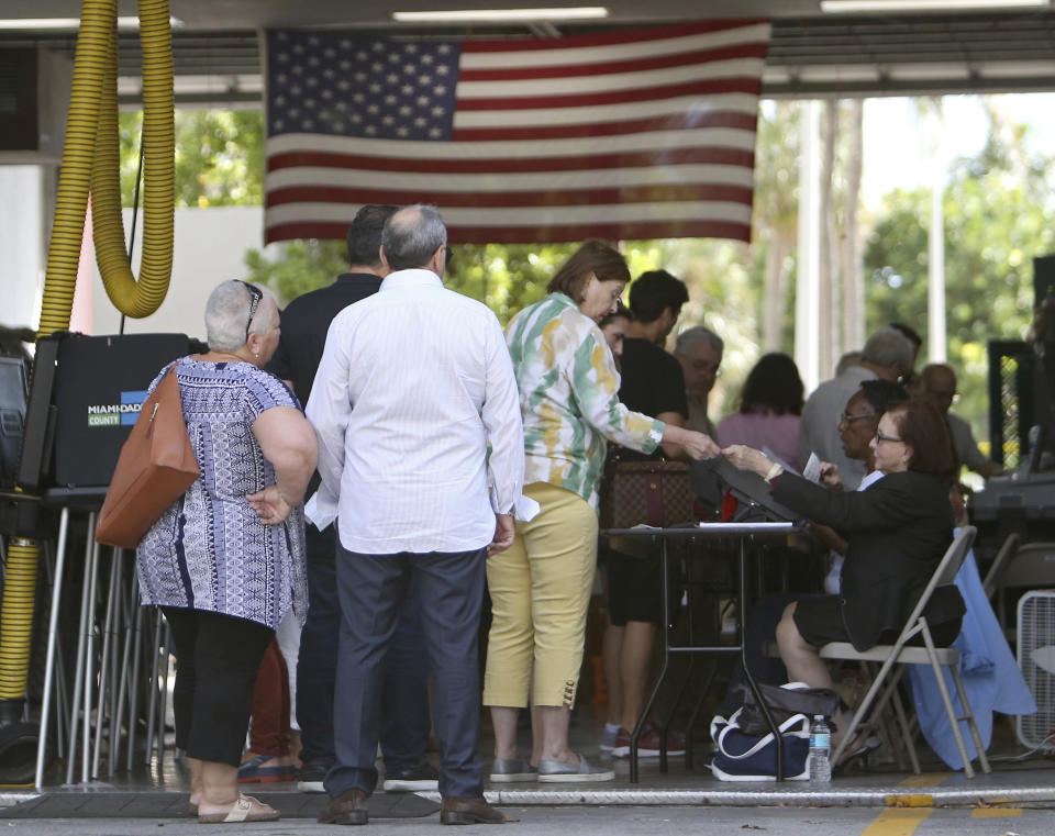 Polling workers help people to check in at Miami Beach Fire Station No. 3 on Tuesday, Nov. 6, 2018, in Miami-Dade County, Fla. (David Santiago/Miami Herald via AP)