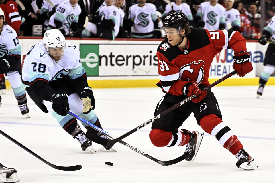 New Jersey Devils center Dawson Mercer (91) handles the puck as Seattle Kraken defenseman Carson Soucy (28) defends during the second period of an NHL hockey game Thursday, Feb. 9, 2023, in Newark, N.J. (AP Photo/Bill Kostroun)