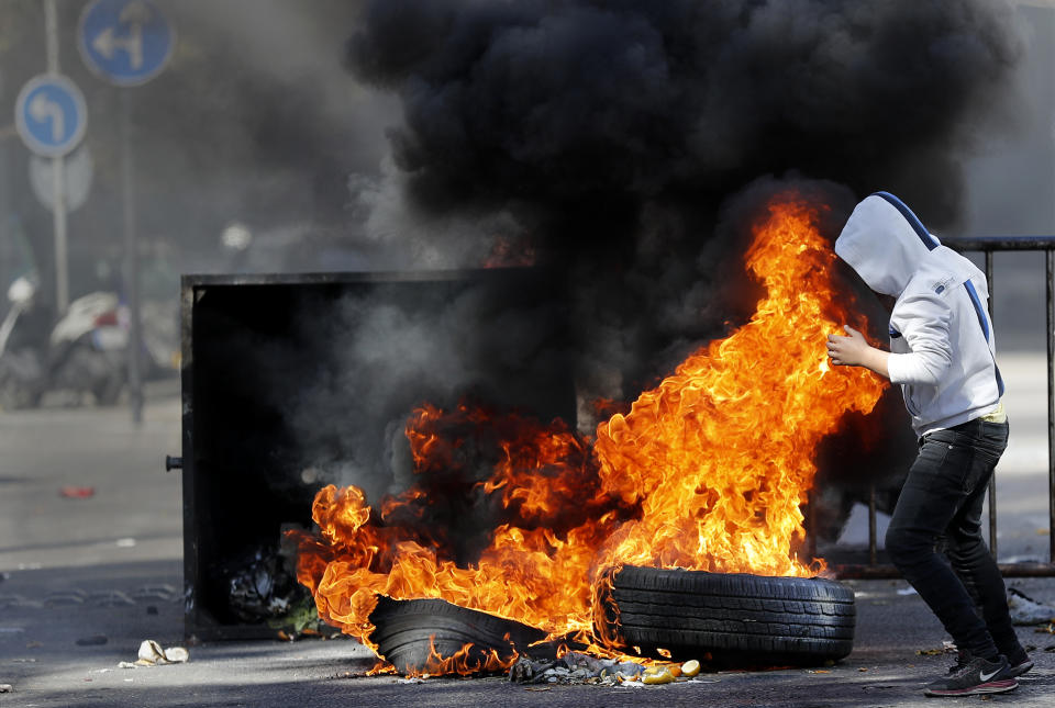 A protester burns tires to block a main road during a protest against the increase in prices of consumer goods and the crash of the local currency, in Beirut, Lebanon, Tuesday, March 16, 2021. Scattered protests broke out on Tuesday in different parts of the country after the Lebanese pound hit a new record low against the dollar on the black market. (AP Photo/Hussein Malla)