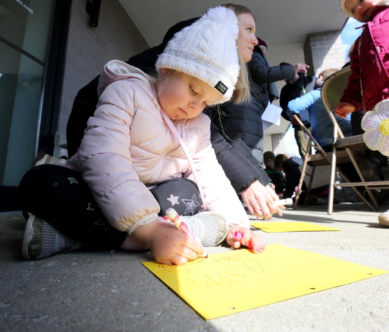 Junia Campbell, 5, draws with her mother, Krissy Campbell, both of South Bend, March 27, 2024, outside the offices of Indiana U.S. Rep. Rudy Yakym, R-2nd, at a prayer vigil for peace by the group Mennonite Action calling on the Congressman to work for a ceasefire in Gaza.