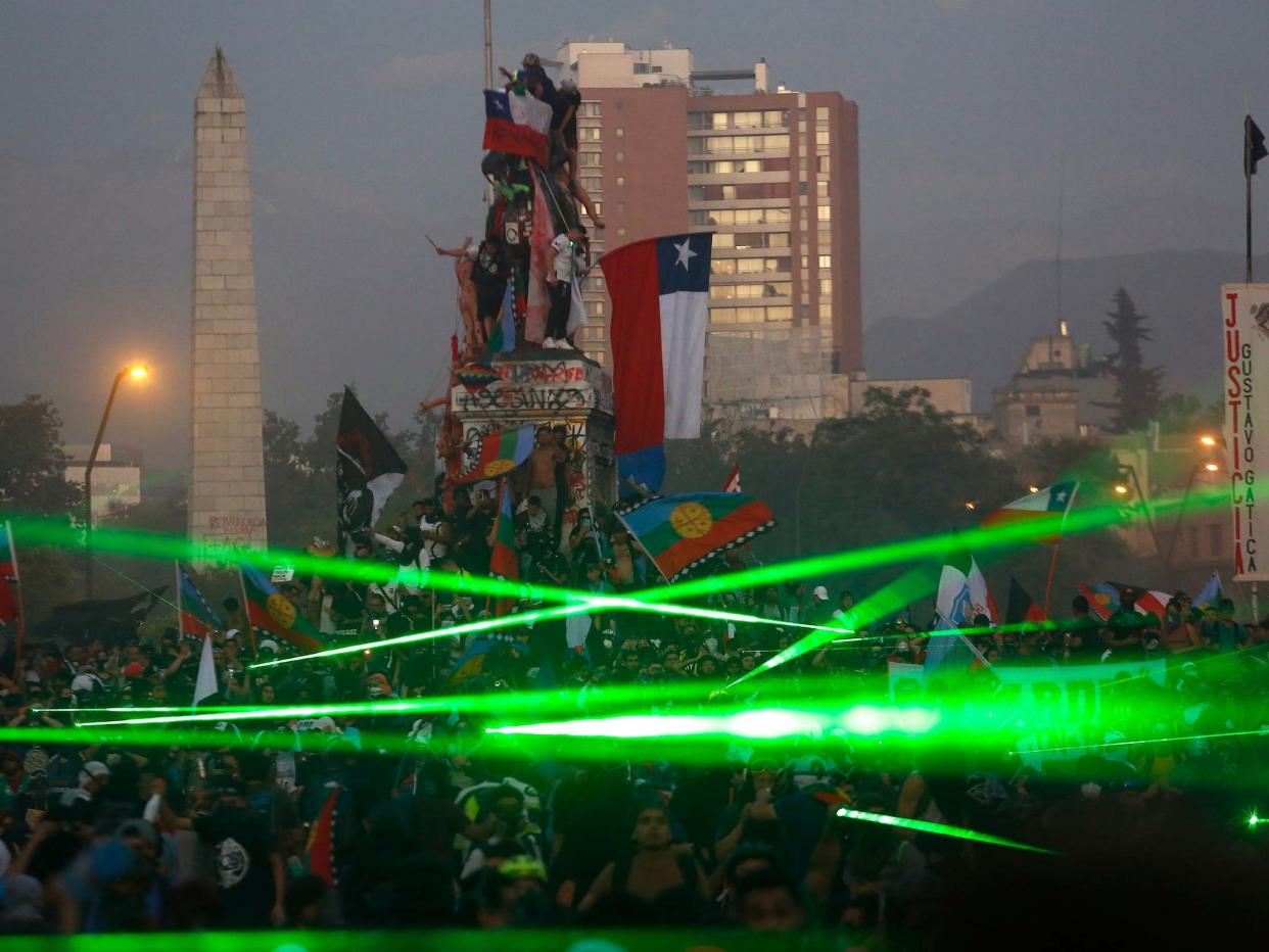 Demonstrators take on riot police using green laser lights in Santiago, Chile, on 15 November: Getty Images