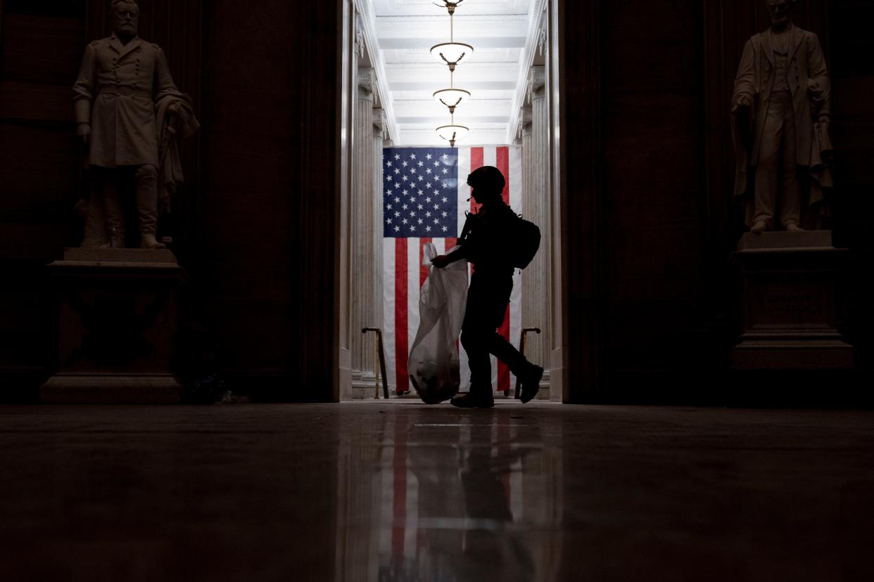 An ATF police officer cleans up debris and personal belongings strewn across the floor of the Rotunda in the early morning hours of Thursday, Jan. 7, 2021, after protesters stormed the Capitol in Washington on Wednesday.