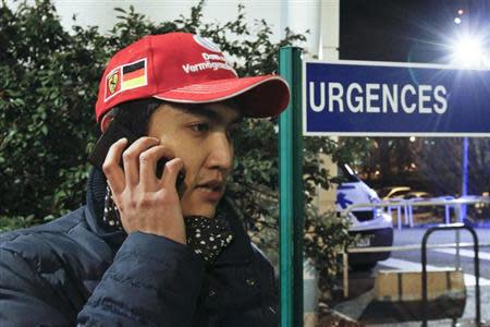 A fan wearing a red cap stands outside the CHU Nord hospital in Grenoble, French Alps, where retired seven-times Formula One world champion Michael Schumacher is hospitalized after a ski accident, December 29, 2013. REUTERS/Robert Pratta