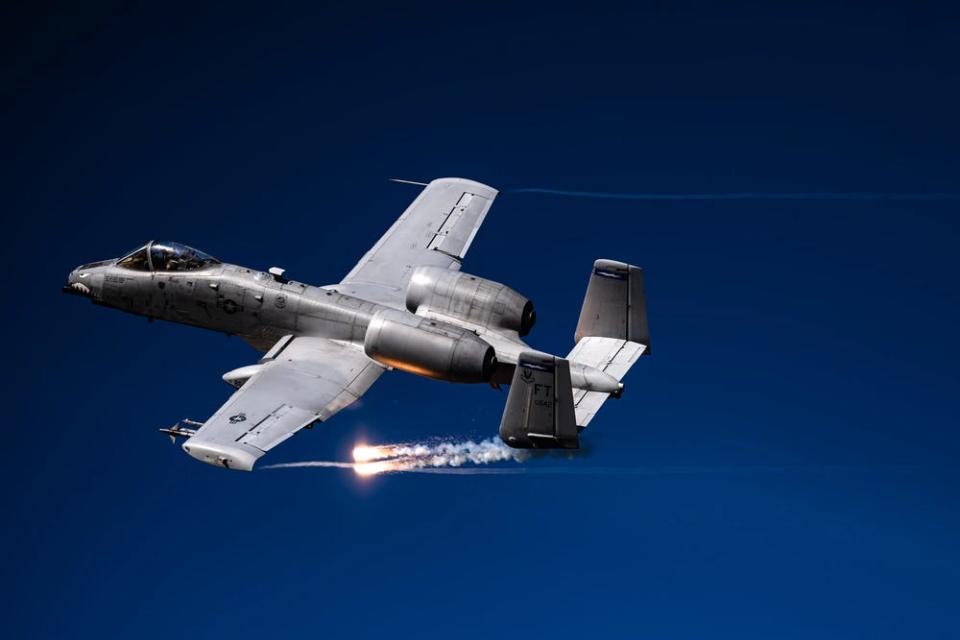 a gray fighter aircraft deploys flares mid-flight