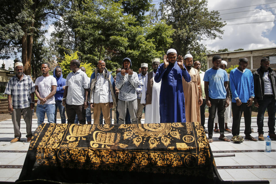 Relatives and friends pray over the body of 13-year-old Yasin Hussein Moyo at his burial, at the Kariakor cemetery in Nairobi, Kenya Tuesday, March 31, 2020. The family of a 13-year-old boy is in mourning after police in Kenya's capital are accused of shooting him dead while enforcing a coronavirus curfew. Kenya’s police inspector general has ordered an investigation into the boy’s death by “stray bullet,” including a forensic analysis of all firearms held by officers at the scene. (AP Photo/Brian Inganga)