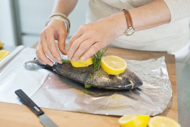 Elderly woman preparing seafood in a kitchen