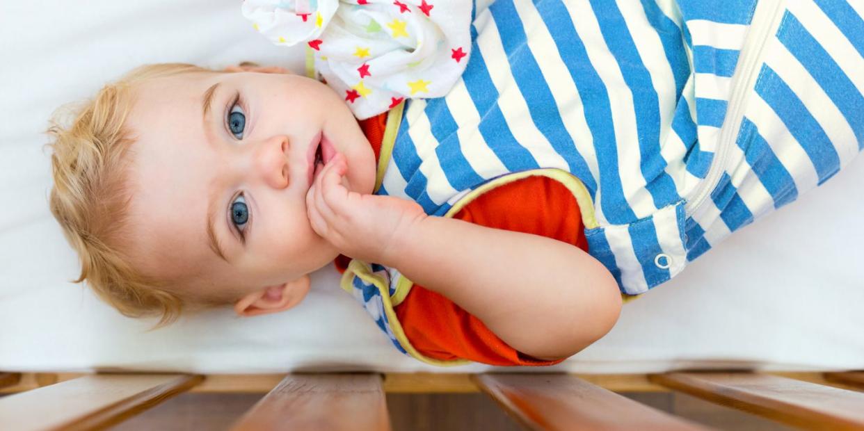 baby wearing striped sleep sack in crib