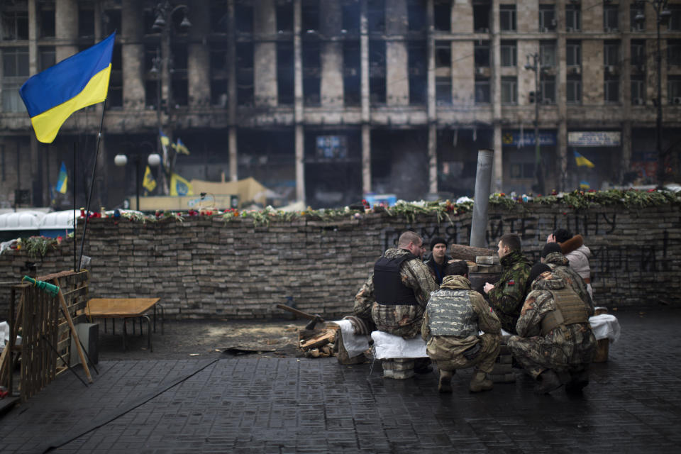 Anti-Yanukovych protesters warm themselves next to a fire as they guard one of the entrance in Kiev's Independence Square, the epicenter of the country's current unrest, Ukraine, Sunday, March 2, 2014. A convoy of hundreds of Russian troops is heading toward the regional capital, Simferopol on the Crimean peninsula in Ukraine today. On the road from Sevastopol, the Crimean port where Russia maintains a naval base, AP journalists saw 12 military trucks. Russian troops took over the strategic Black Sea peninsula yesterday and are ignoring international protests. (AP Photo/Emilio Morenatti)