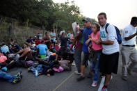 Migrants from Central America and Cuba rest on a highway as others help a fellow migrant with health problems during their journey towards the United States, in Tuzantan, in Chiapas state, Mexico March 25, 2019. REUTERS/Jose Torres