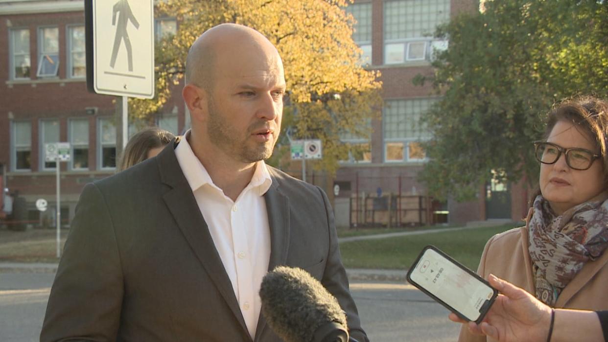 Official opposition critic for education Matt Love stands next to leader Carla Beck at a news conference for the rood hole at Monique-Rousseau elementary school on Tuesday.  (Albert Couillard/CBC - image credit)