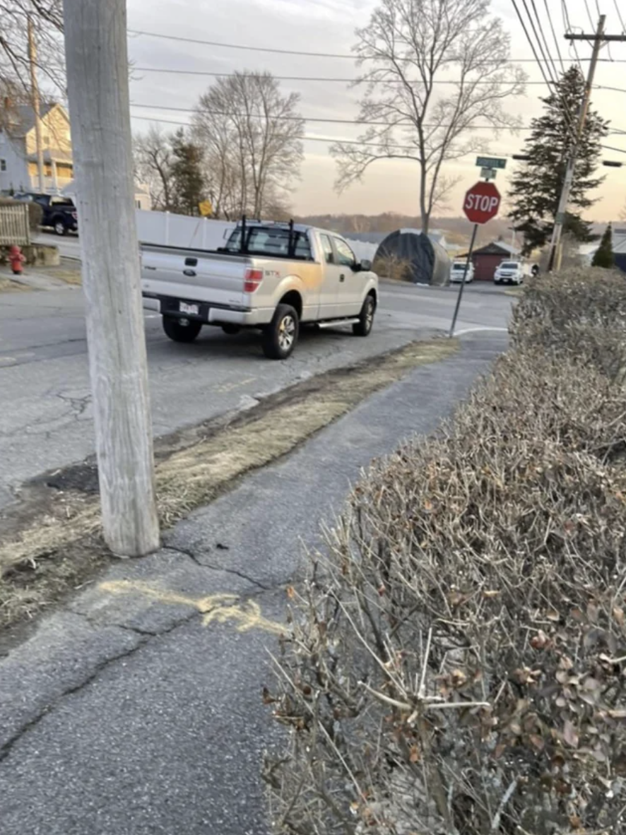 A car is parked in front of a stop sign and not next to a curb