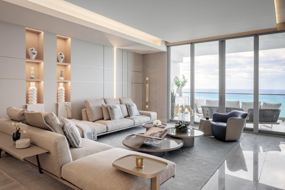 For this residence at the Estates at Acqualina, FL Interiors employed a modern, coastal aesthetic to lend the living space a relaxing air. An ample sectional is surrounded by low tables, sculptural lighting, and luxury finishes, and a well-appointed outdoor area sits adjacent.