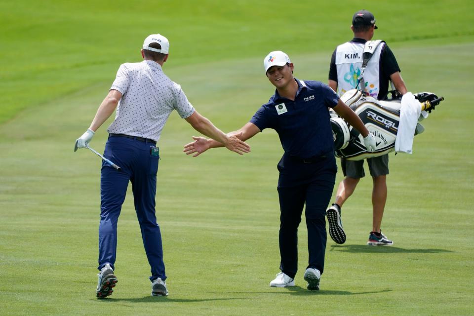 Si Woo Kim, of South Korea, center, shakes hands with Mackenzie Hughes after Kim made an eagle from the 18th fairway during the first round of the St. Jude Championship golf tournament Thursday, Aug. 11, 2022, in Memphis.