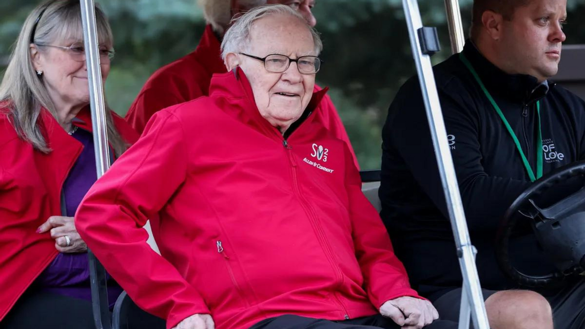 A white man sits in a golf cart surrounded by three other people. 