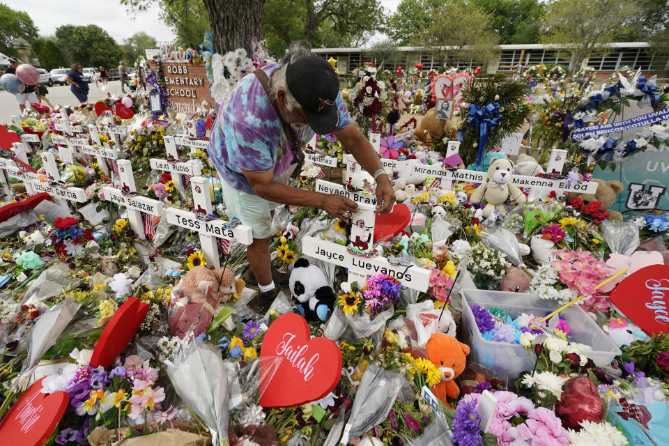 A visitor places bracelets on crosses labeled with the names of victims in the Uvalde shooting.