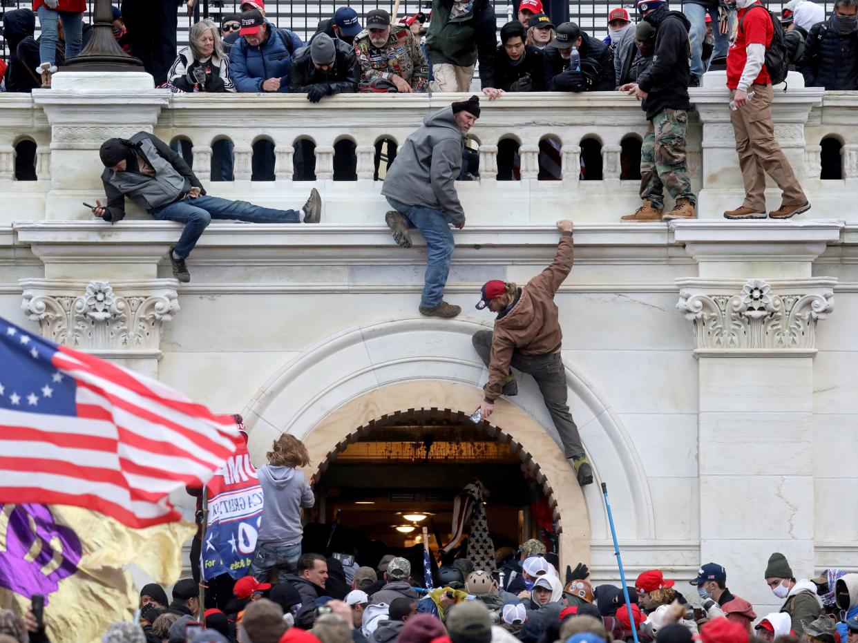 A mob of supporters of then President Donald Trump fights with members of law enforcement at a door they broke open as they storm the Capitol Building in Washington, on 6 January 2021 (REUTERS)