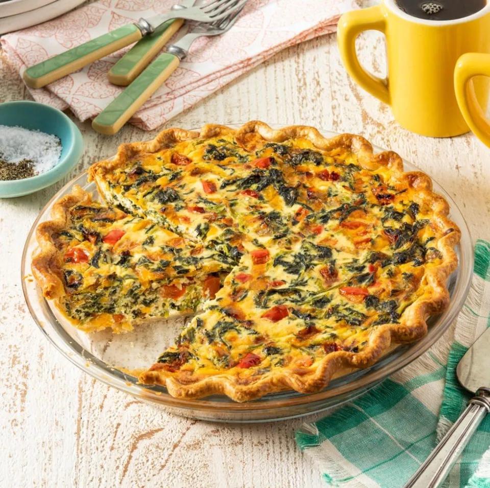 spinach quiche in glass pan with yellow mug of coffee