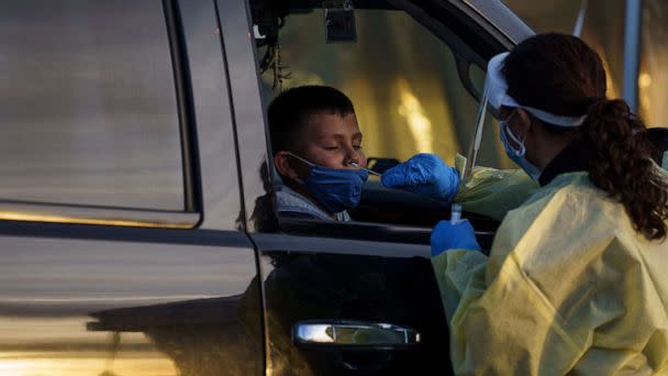 PHOTO: Healthcare worker Azucena Estrada gives five-year-old Gabriel Govea a nasal swab samples at a drive-thru COVID-19 testing site in El Paso, Texas, Jan. 12, 2022. (Paul Ratje/AFP via Getty Images)