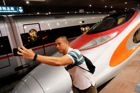 A passenger poses next to the first train that departed from Hong Kong during the first day of service of the Hong Kong Section of the Guangzhou-Shenzhen-Hong Kong Express Rail Link, in Shenzhen, China September 23, 2018. REUTERS/Tyrone Siu
