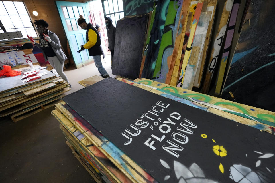Plywood mural boards are lined up at a warehouse, Saturday, Dec. 12, 2020, in Minneapolis ready for volunteers to help organize them. Leesa Kelly, left background, and Kenda Zellner-Smith, right in yellow, formed the Save the Boards to Memorialize the Movement to preserve the painted expressions and pain born of outrage after the death of George Floyd at the hands of Minneapolis police in May. (AP Photo/Jim Mone)