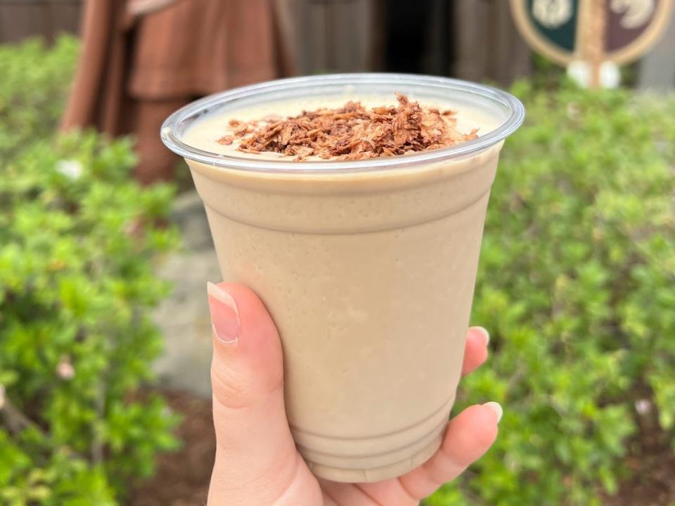 hand holding plastic cup of frozen coffee drink from norway in epcot
