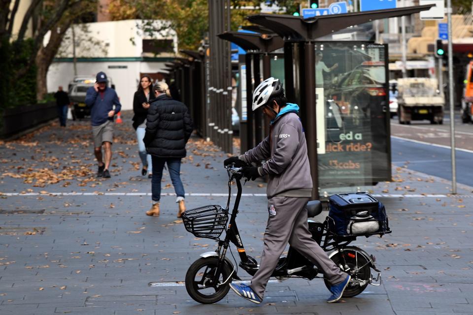 A courier crosses the road to deliver food in the central business district in Sydney on May 14, 2020. - Almost 600,000 Australians lost their jobs as the virus shutdown took hold in April, the steepest monthly drop since records began more than 40 years ago, data showed on May 14. (Photo by Saeed KHAN / AFP) (Photo by SAEED KHAN/AFP via Getty Images)