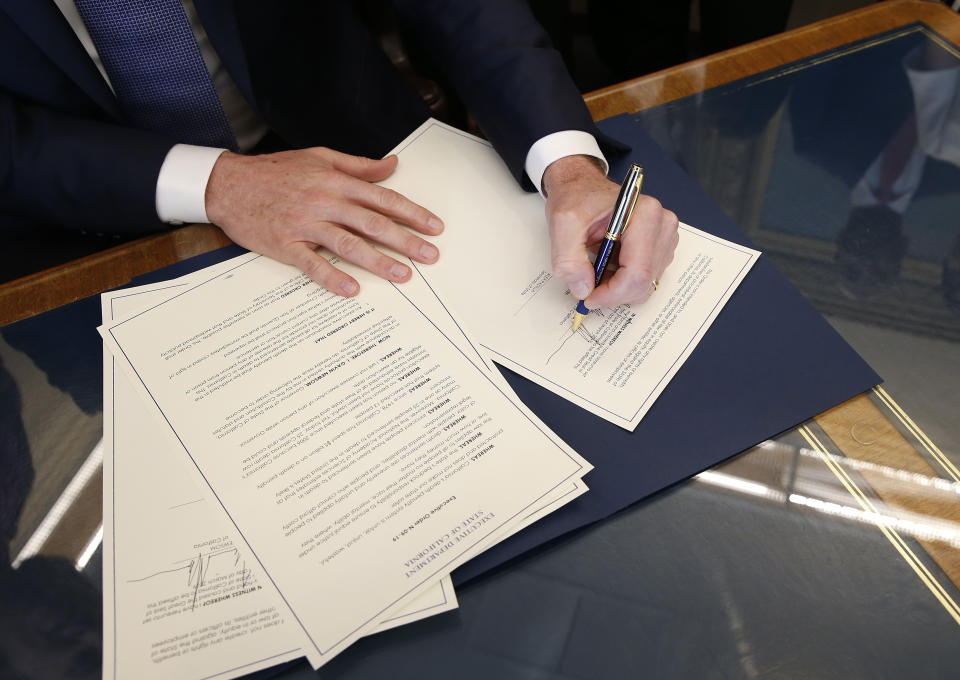 Gov. Gavin Newsom signs the executive order placing a moratorium on the death penalty at his Capitol office Wednesday, March 13, 2019, in Sacramento, Calif. (AP Photo/Rich Pedroncelli)