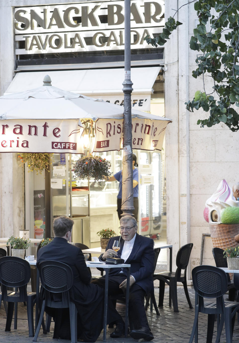 Cardinal George Pell has a drink in a cafe at the Vatican, Sunday, Oct. 4, 2020. Cardinal George Pell, who left the Vatican in 2017 to face child sexual abuse charges in Australia, returned to Rome on Wednesday to find a Holy See mired in the type of corruption scandal he worked to expose and clean up. (AP Photo/Gregorio Borgia)