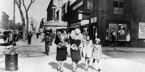 <p>Women and children stroll down the streets of Harlem in New York City during the winter of 1933. </p>