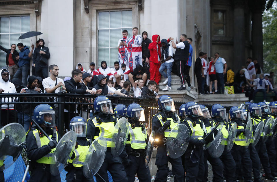 FILE - Supporters stand behind a police line near Trafalgar Square in London, during the Euro 2020 soccer championship final match between England and Italy which is being played at Wembley Stadium on July 11, 2021. An investigation into the disorder at the European Championship final says aggression by England fans exposed an “embarrassing” part of the national culture that endangered lives and should lead to entry to stadiums being prohibited to anyone chanting abuse and high on drugs or drunk. (AP Photo/Peter Morrison, File)