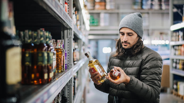 man picking out whiskey at a store