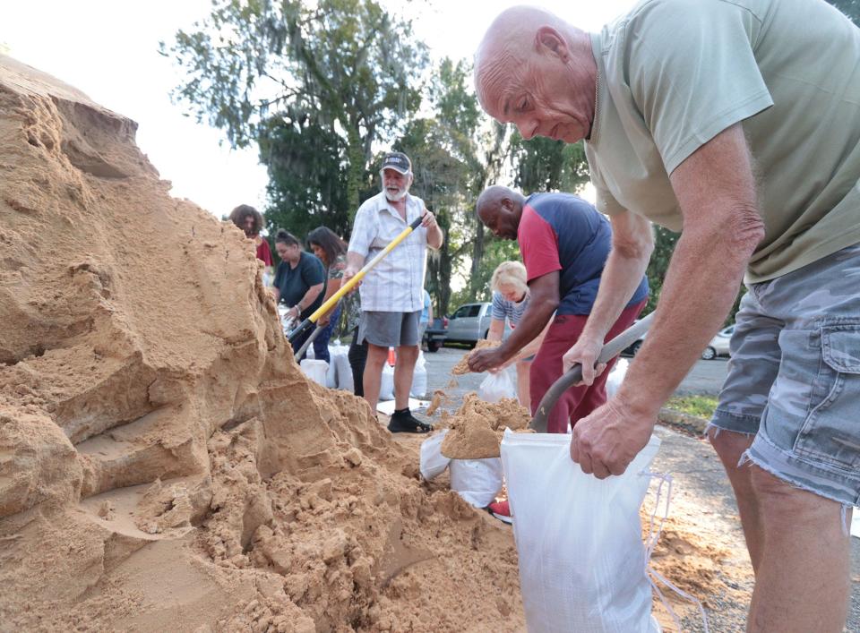 As Hurricane Ian churns toward Florida's Gulf Coast, Phil Marshall fills a sandbag with other residents on Monday morning at a sandbag distrubution location on Jean Street in Daytona Beach.