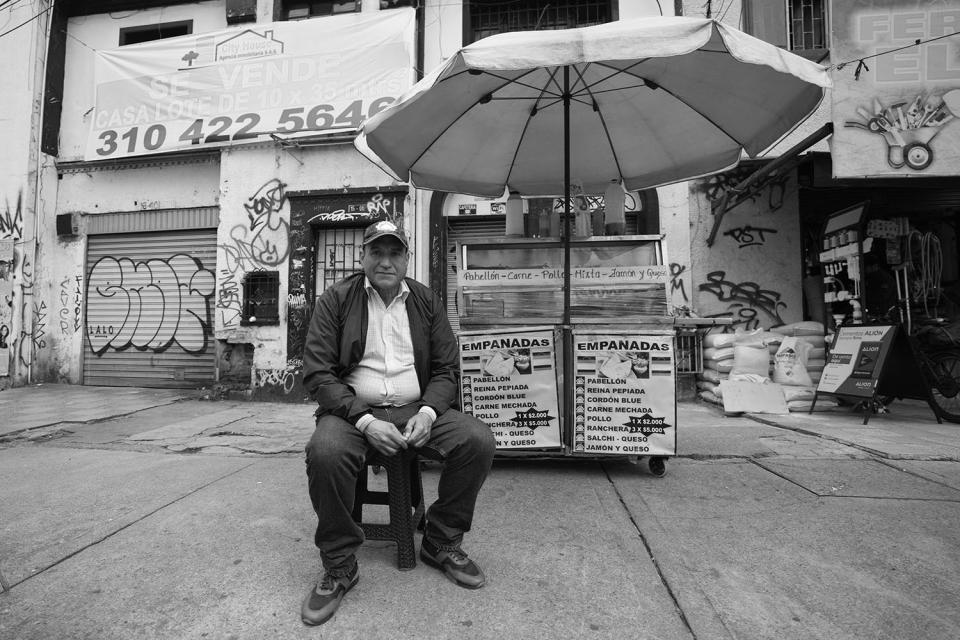 HOLD FOR DARIO LOPEZ - Ángel Bruges, from Venezuela, poses for a portrait at his empanada stand in Bogota, Colombia, Wednesday, Feb. 22, 2023. Bruges and his wife began selling empanadas from a cart when they moved here in 2019, parlayed that cart into a shop and three larger carts and used some of their earnings to relocate their daughter to Bogota last year. (AP Photo/Fernando Vergara)