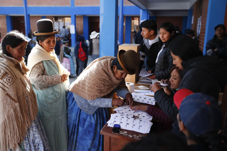A woman signs on a voters record after voting at a polling station during general elections in La Paz outskirts, Bolivia, Sunday, Oct. 20, 2019. Bolivians are voting in general elections Sunday where President Evo Morales is Presidential candidate for a fourth term. (AP Photo/Jorge Saenz)