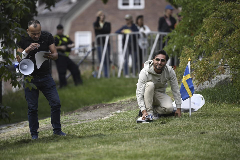 Protestor Salwan Momika kneels next to a Swedish flag outside the Iraqi embassy in Stockholm, Thursday, July 20, 2023, where he plans to burn a copy of the Quran and the Iraqi flag. (Oscar Olsson/TT via AP)