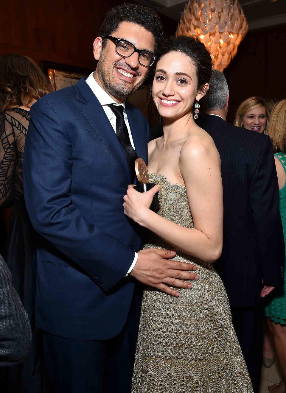 <p>The <i>Shameless</i> alumna and <i>Mr. Robot </i>creator Sam Esmail shared a fondness for <i>The</i> <i>New York Times</i>' "Modern Love" section, so it only makes sense that the romantic column would play a part in their own story.</p> <p>Speaking to <a href="https://www.vogue.com/article/emmy-rossum-wedding-2017-carolina-herrera?mbid=social_twitter" rel="nofollow noopener" target="_blank" data-ylk="slk:Vogue;elm:context_link;itc:0;sec:content-canvas" class="link "><i>Vogue</i></a> after her <a href="https://people.com/style/emmy-rossum-marries-sam-esmail-wedding/" rel="nofollow noopener" target="_blank" data-ylk="slk:2017 wedding;elm:context_link;itc:0;sec:content-canvas" class="link ">2017 wedding</a>, Rossum opened up about the way <a href="https://people.com/tv/emmy-rossum-engaged-to-sam-esmail/" rel="nofollow noopener" target="_blank" data-ylk="slk:they got engaged;elm:context_link;itc:0;sec:content-canvas" class="link ">they got engaged</a> two years earlier. </p> <p>"I do a dramatic reading of it for him. Even if we're not in the same place, I read it to him over the phone," the actress explained of their "Modern Love" tradition. "Then one weekend we didn't read it—I don't remember why exactly—and the following Friday he reminded me that we hadn't. I was actually in kind of a bad mood that day, so I said, 'Oh, well I'll read it eventually.' And he said, 'No, no, no, I think you should read it.' And I said, 'I'm having a back spasm. I'm actually going to take a bath and have a glass of wine, but if you really want to hear it I'll read it to you from the bathtub."</p> <p>"I began to read the article, and the story is about a director who falls in love with an actress, and I started to think: Huh, that's strange. And then I realized that it was our love story. At first, I freaked out because I thought perhaps he had actually put it in the paper and I hadn't seen it, and everyone knew it but me."</p> <p>Rossum soon realized that her husband had gone to lengths to ask her to marry him. "Apparently he had called Daniel Jones at <i>The New York Times</i> and gotten their paper template and gotten the people there to print out a whole mock section on the bottom half. He had even put an ad for the Ralph Lauren Ricky Bag," she said. "By the time I finished the story he was down on a knee in the bathroom, with me in the tub."</p>