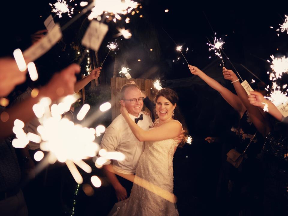 Couple embracing in the center of a tunnel of held sparklers at wedding