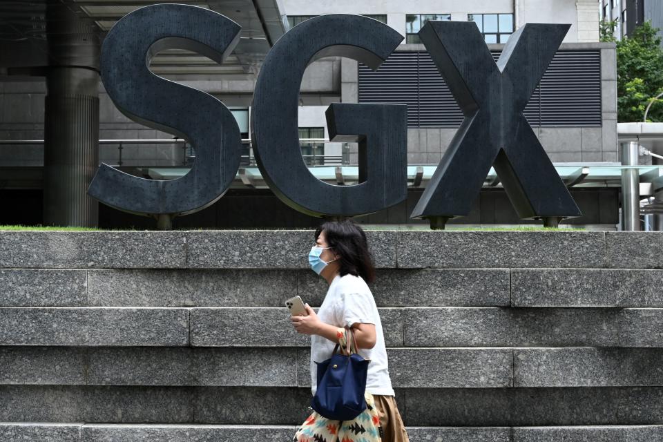 A woman, wearing a face mask as a preventive measure against the spread of the COVID-19 novel coronavirus, walks past the Singapore Exchange (SGX) stock exchange building in the central business district are in Singapore on April 7, 2020. - Singapore's usually bustling business district was almost deserted on April 7 as most workplaces in the city-state closed to stem the spread of the coronavirus after a surge in cases. (Photo by Roslan RAHMAN / AFP) (Photo by ROSLAN RAHMAN/AFP via Getty Images)